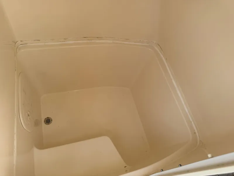 Slide: The Image of 2020 Cobia 220 Center Console storage compartment, beige interior, with drain. - 47