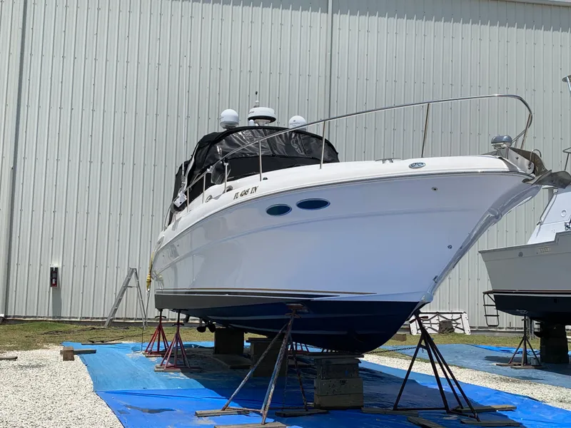 Slide: The Image of 2002 Sea Ray 340 Sundancer yacht on stands, outside a large metal building. - 1
