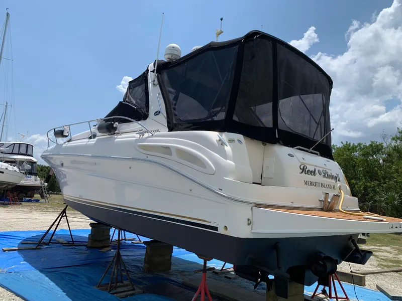 Slide: The Image of 2002 Sea Ray 340 Sundancer yacht on stands, covered, under clear sky. - 2