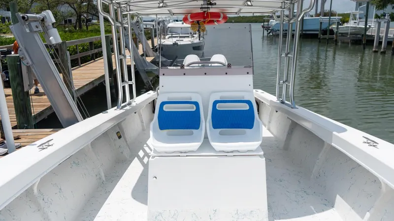Slide: The Image of 2021 C-Hawk 29CC boat interior with blue seats, docked at a marina. - 15
