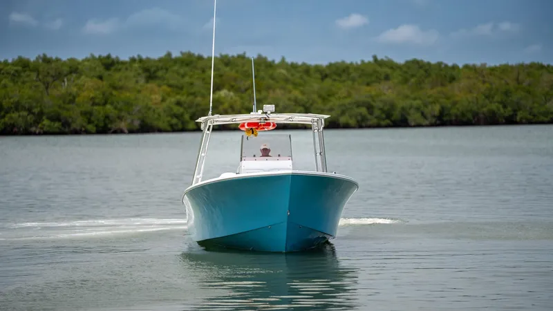 Slide: The Image of 2021 C-Hawk 29CC boat cruising on calm water with lush greenery in the background. - 4