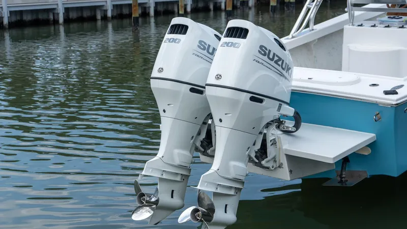 Slide: The Image of Twin Suzuki outboard motors on a 2021 C-Hawk 29CC boat, docked in calm water. - 6