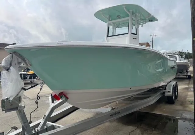 Slide: The Image of 2025 NauticStar 252 Legacy boat on trailer, light blue hull, overcast sky. - 2