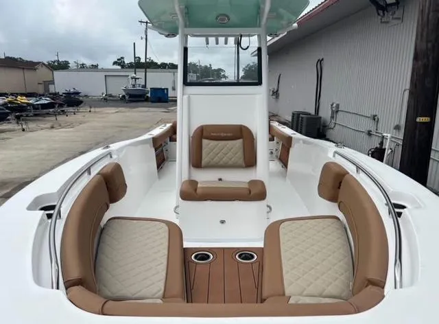 Slide: The Image of 2025 NauticStar 252 Legacy boat with tan seating and cup holders in a marina setting. - 6