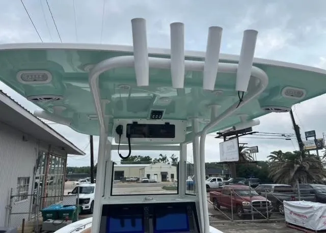 Slide: The Image of 2025 NauticStar 252 Legacy boat with rod holders and electronics, docked under cloudy skies. - 9