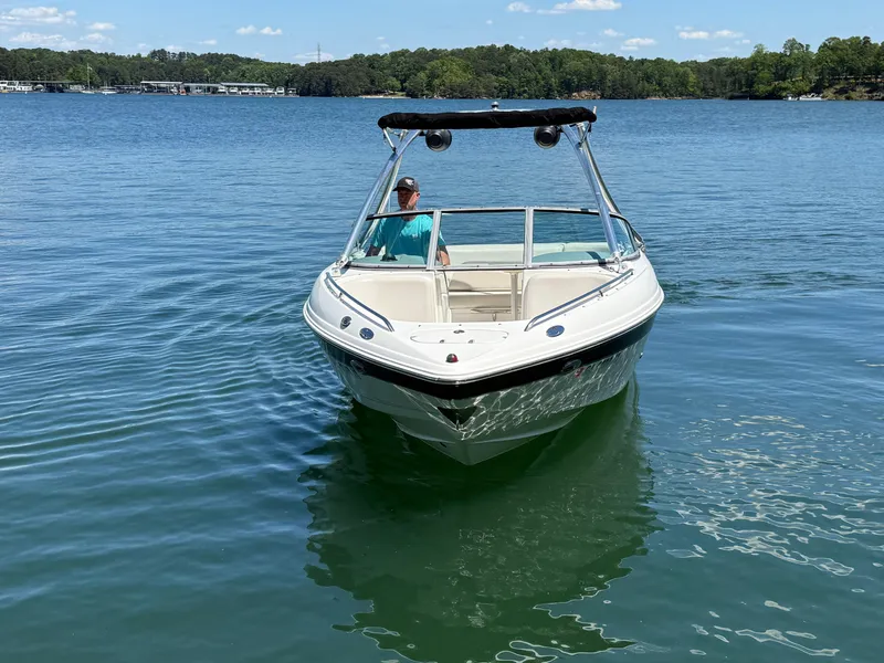 Slide: The Image of 2006 Chaparral 220 SSi boat on a calm lake with a person at the helm. - 2