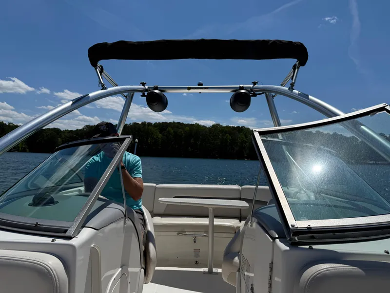 Slide: The Image of 2006 Chaparral 220 SSi boat on a sunny lake, featuring open windshield and canopy. - 32