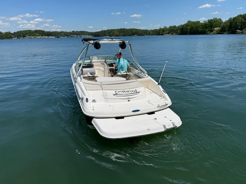 Slide: The Image of 2006 Chaparral 220 SSi boat cruising on a serene lake under a clear blue sky. - 9