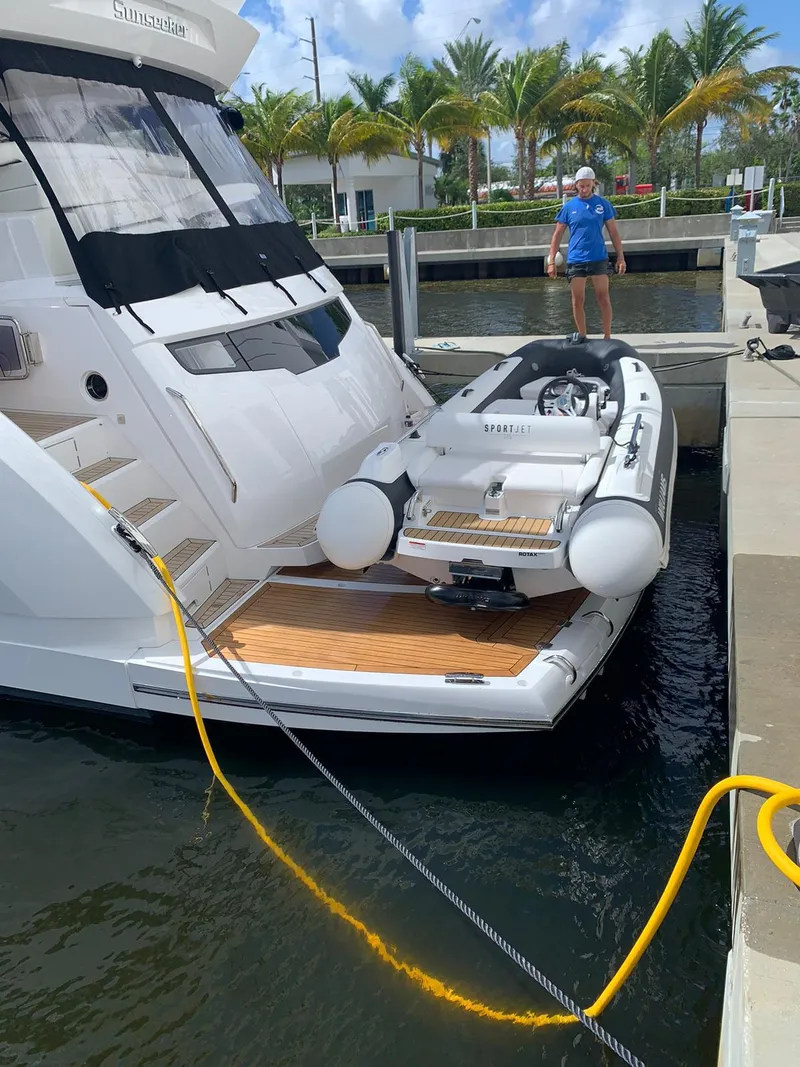 Slide: The Image of Sunseeker Manhattan 68 yacht with a small inflatable boat docked at a marina, 2020 model. - 7