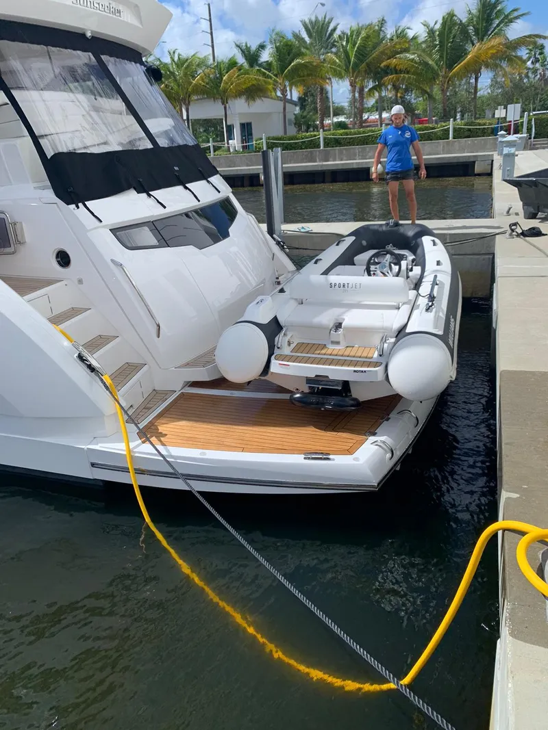 Slide: The Image of 2020 Sunseeker Manhattan 68 yacht with a small tender docked at a marina. - 8