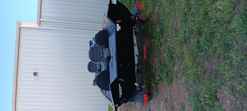Slide: The Image of 2025 Tracker Pro Team 195 Tournament Edition boat on trailer, parked beside a building. - 2