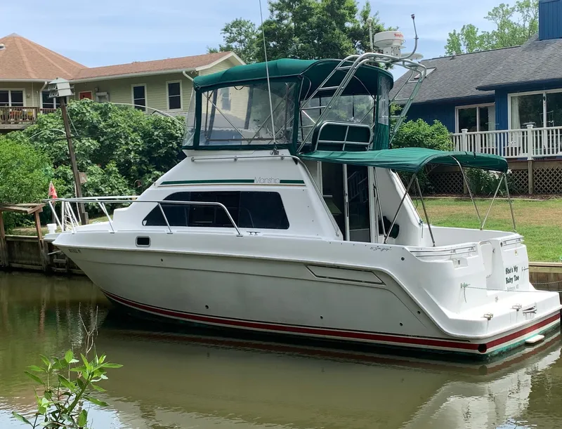 The Image of 1994 Mainship 31 Sedan Bridge boat docked by waterfront homes. - 0