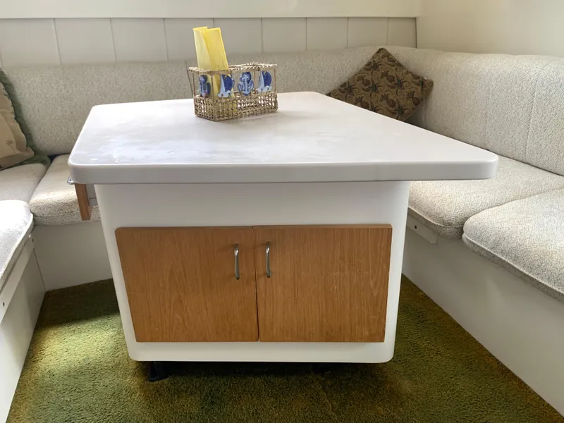 Slide: The Image of 1994 Mainship 31 Sedan Bridge interior with table, cushioned seating, and decorative basket. - 11