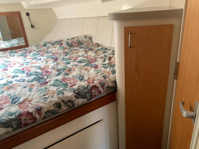 Slide: The Image of 1994 Mainship 31 Sedan Bridge cabin with floral bedding and wooden cabinetry. - 16