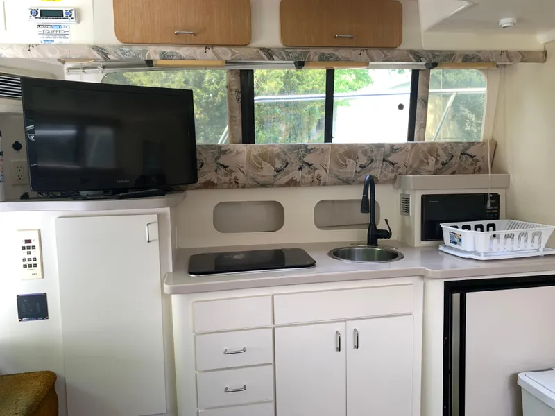 Slide: The Image of 1994 Mainship 31 Sedan Bridge interior with kitchenette, TV, and microwave. - 2