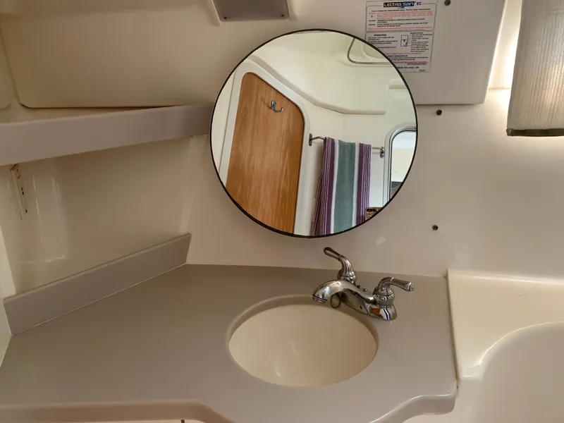 Slide: The Image of Bathroom vanity with round mirror and faucet in 1994 Mainship 31 Sedan Bridge. - 20