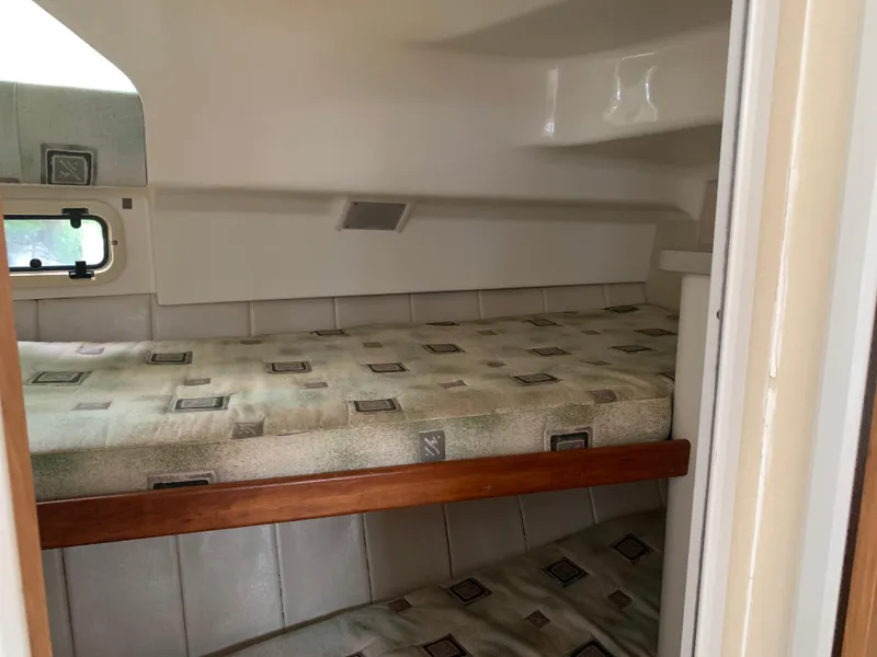 Slide: The Image of 1994 Mainship 31 Sedan Bridge cabin with bunk beds and patterned bedding. - 25