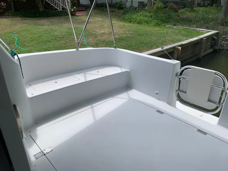 Slide: The Image of 1994 Mainship 31 Sedan Bridge boat deck with seating, near a grassy yard and dock. - 27