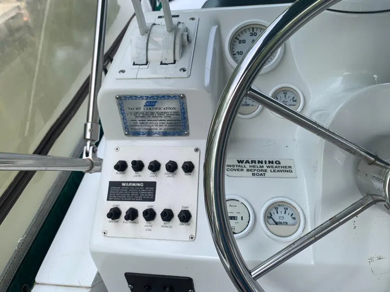 Slide: The Image of 1994 Mainship 31 Sedan Bridge helm with gauges, controls, and yacht certification plaque. - 40