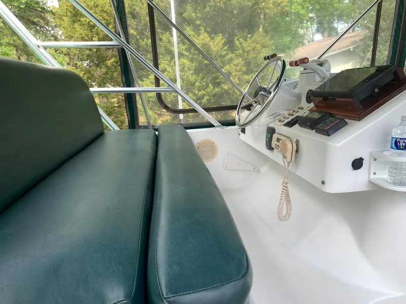 Slide: The Image of 1994 Mainship 31 Sedan Bridge helm with green seating, steering wheel, and navigation equipment. - 41