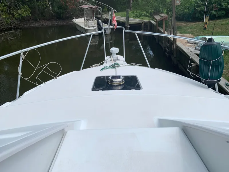 Slide: The Image of Bow view of 1994 Mainship 31 Sedan Bridge docked in a narrow waterway. - 47