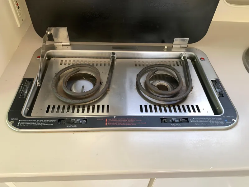 Slide: The Image of 1994 Mainship 31 Sedan Bridge stove with two coiled burners, alcohol-fueled, in a compact kitchen setting. - 6