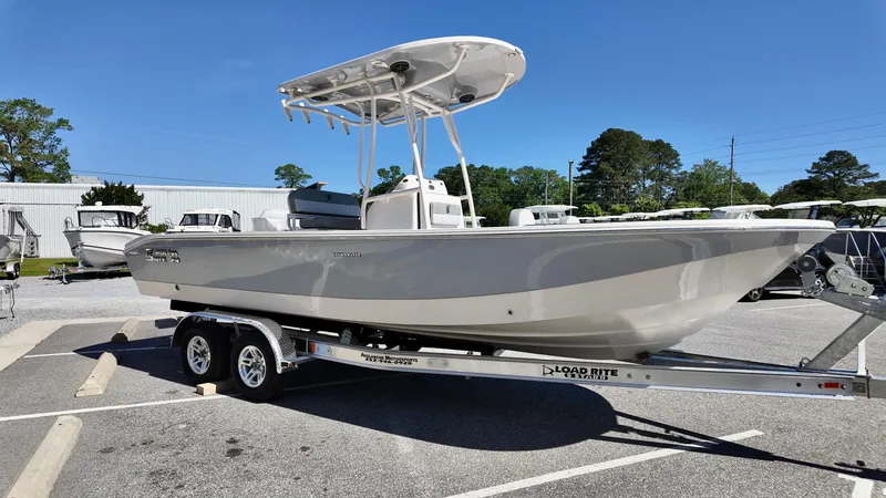 Slide: The Image of 2025 Carolina Skiff 24 Ultra Elite boat on trailer, parked outdoors under clear blue sky. - 3