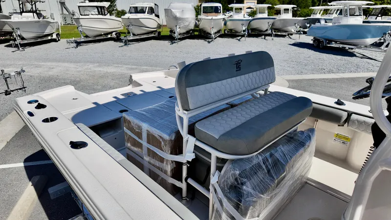 Slide: The Image of 2025 Carolina Skiff 24 Ultra Elite boat interior with seating, parked among other boats. - 7