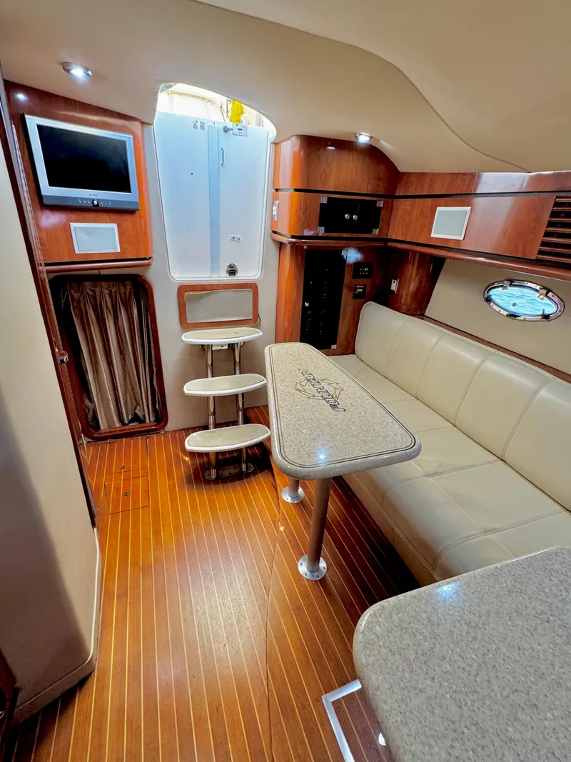 Slide: The Image of 2005 Fountain 48 Express Cruiser interior with wood flooring, beige seating, and a mounted TV. - 12