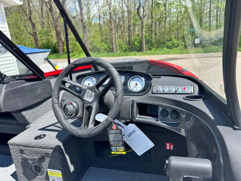 Slide: The Image of 2025 Crestliner 1750 Hawk boat dashboard with steering wheel and gauges, surrounded by trees. - 5
