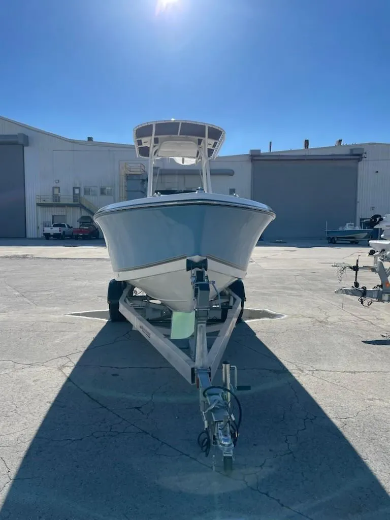 Slide: The Image of 2025 Mako 214 Center Console boat on trailer, parked outdoors under clear blue sky. - 4