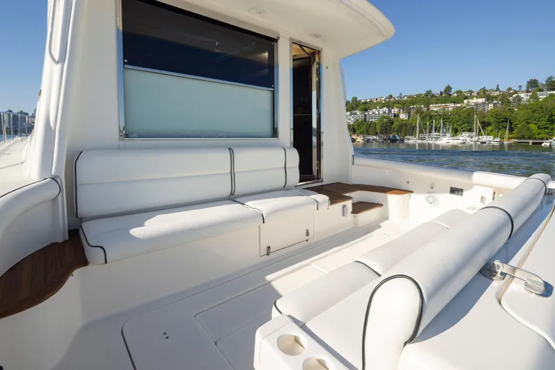 Slide: The Image of 2005 Tiara Yachts 5200 Sovran Salon with spacious white seating on deck, docked by lush shoreline. - 15