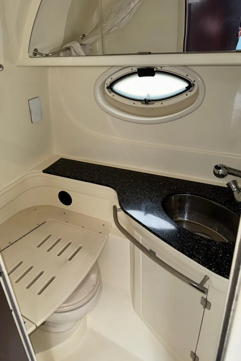Slide: The Image of 2013 Monterey 320 Sport Yacht bathroom with sink, toilet, and porthole window. - 49