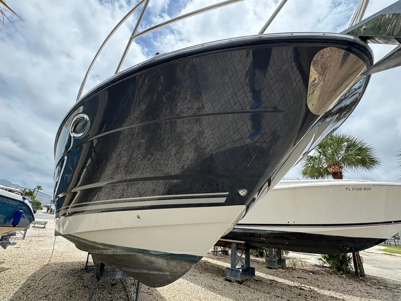 Slide: The Image of 2013 Monterey 320 Sport Yacht on display, sleek black hull, parked on gravel. - 5