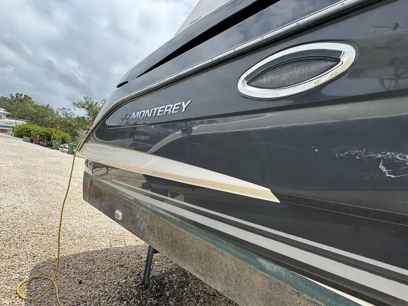 Slide: The Image of 2013 Monterey 320 Sport Yacht, gray hull, parked on gravel, side view. - 6
