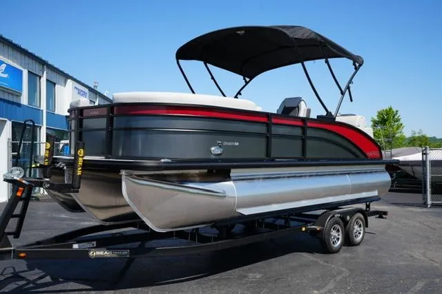 Slide: The Image of 2025 Harris Cruiser 210 pontoon boat on trailer, black and red design, outdoor display. - 1