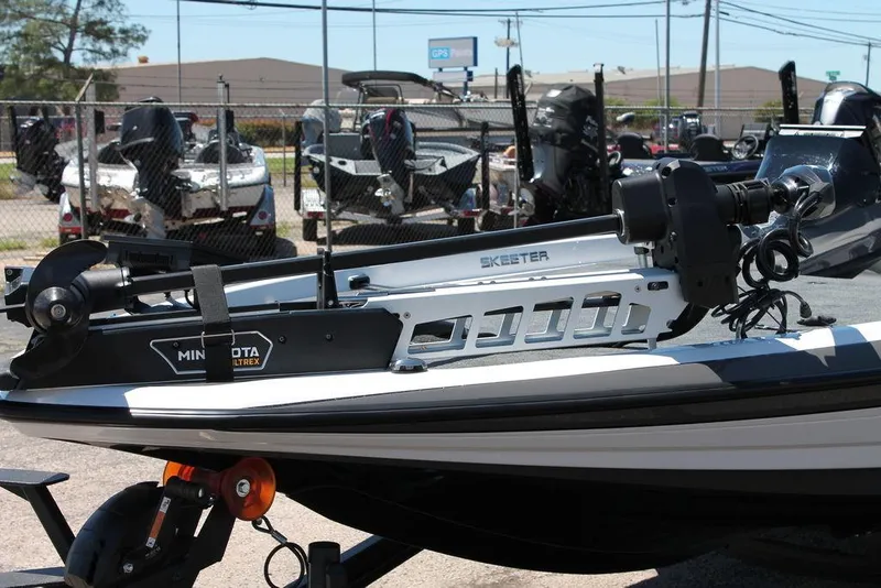 Slide: The Image of 2025 Skeeter ZXR21 boat with Minn Kota trolling motor, parked in a marina. - 7