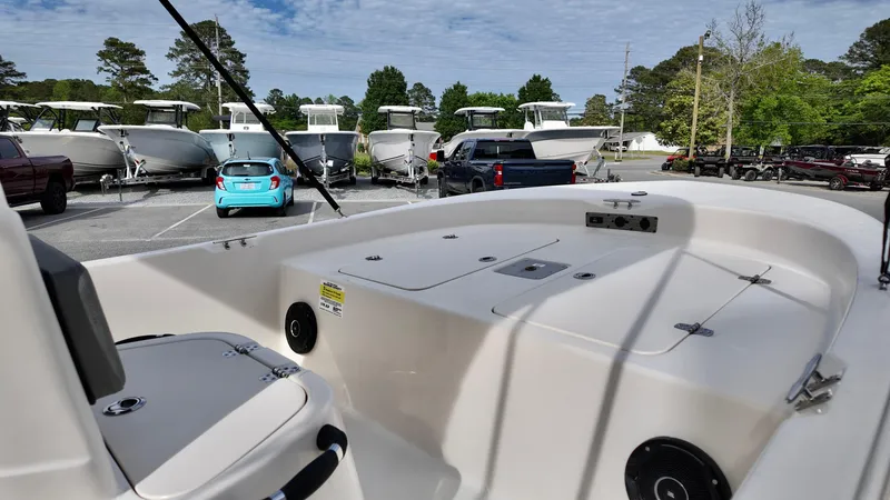 Slide: The Image of 2025 Carolina Skiff 178 JLS CC boat interior at a dealership with parked cars and boats. - 11