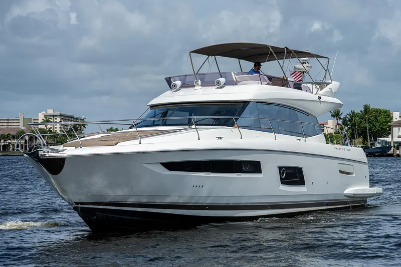 Slide: The Image of Luxury 2014 Prestige 550 yacht cruising on a calm waterway under a cloudy sky. - 11