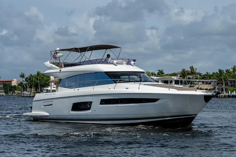 Slide: The Image of 2014 Prestige 550 yacht cruising on a calm waterway under a cloudy sky. - 14