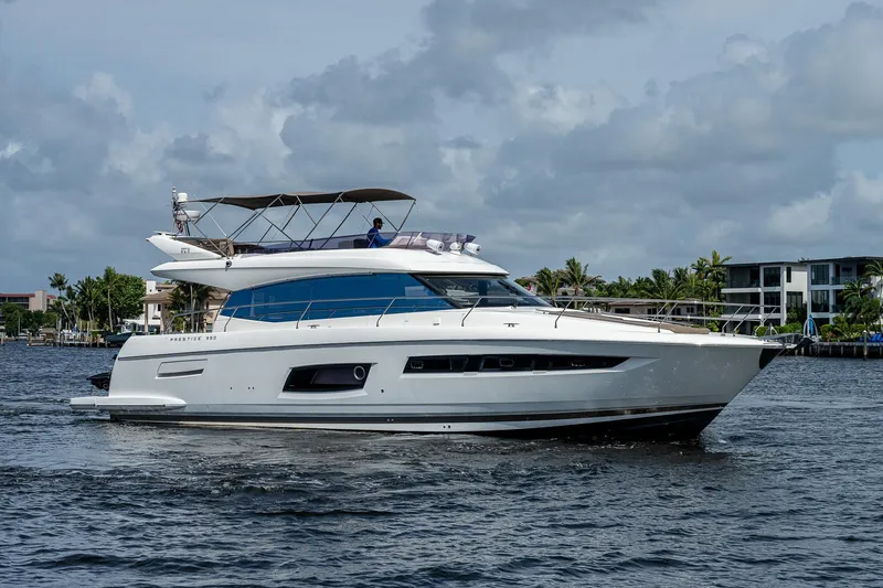 Slide: The Image of 2014 Prestige 550 yacht cruising on a calm waterway under a cloudy sky. - 15