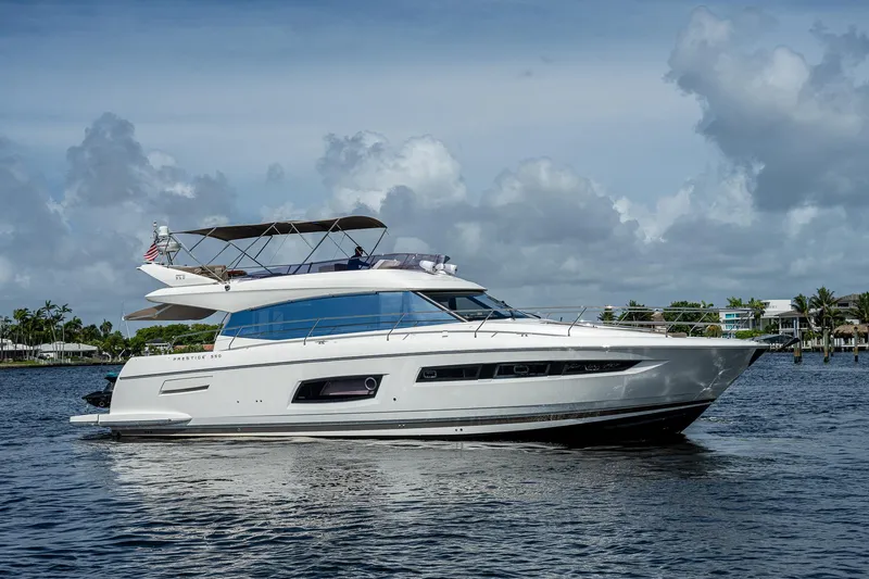 Slide: The Image of 2014 Prestige 550 yacht cruising on a calm, scenic waterway under a partly cloudy sky. - 16
