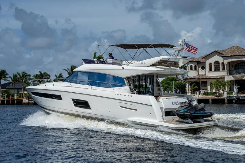 Slide: The Image of 2014 Prestige 550 yacht cruising on water near luxury waterfront homes. - 19