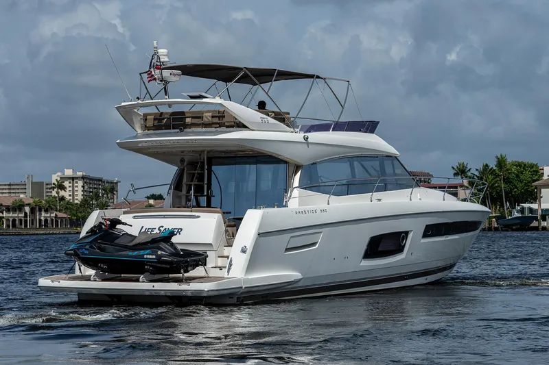 Slide: The Image of 2014 Prestige 550 yacht cruising with jet ski on deck, under cloudy sky. - 2