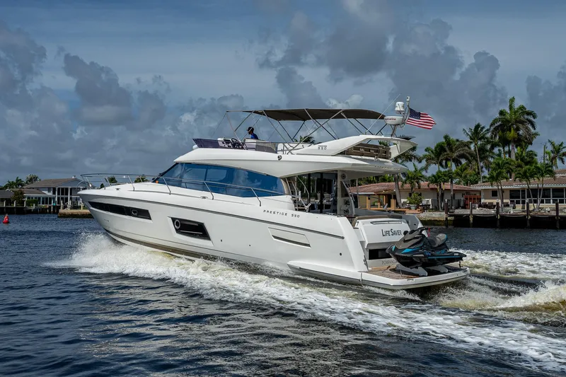 Slide: The Image of 2014 Prestige 550 yacht cruising on a sunny day, with palm trees in the background. - 20