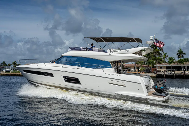 Slide: The Image of 2014 Prestige 550 yacht cruising on a sunny day with palm trees in the background. - 21