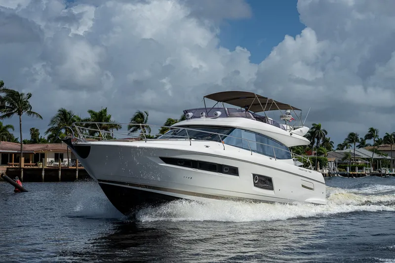 Slide: The Image of 2014 Prestige 550 yacht cruising on a sunny day with palm trees in the background. - 26