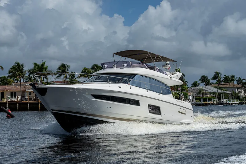 Slide: The Image of 2014 Prestige 550 yacht cruising on a sunny day with palm trees in the background. - 27