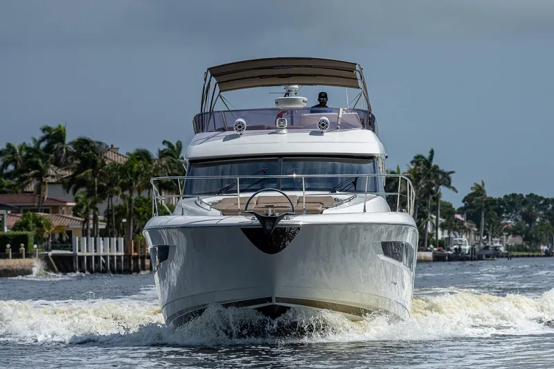Slide: The Image of 2014 Prestige 550 yacht cruising on a scenic waterway with palm trees in the background. - 29