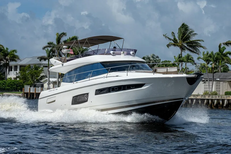 Slide: The Image of 2014 Prestige 550 yacht cruising on a sunny day with palm trees in the background. - 32
